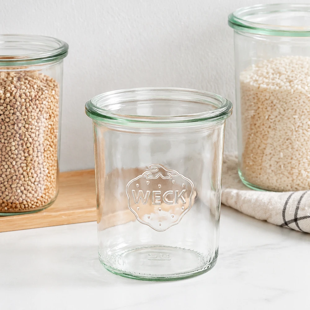 160ml stortglas WECK RR60 WECK 160ml RR60 mason jar met groene rand en logo, lege mason jar naast gevulde voorraadpotten op houten plank